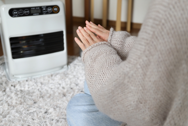 電気ストーブで手を暖める人