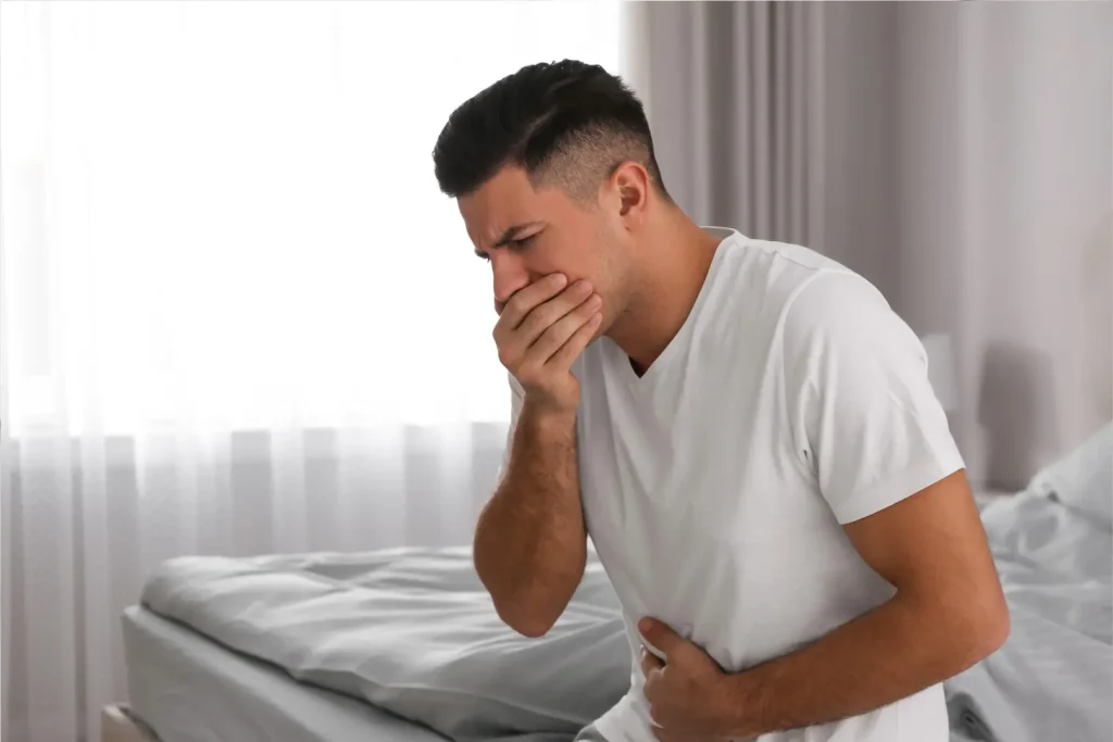口と腹を押さえて吐きそうになる男性