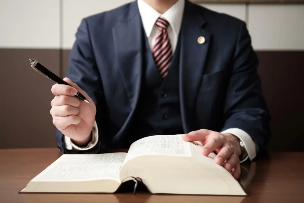 分厚い書類を広げてペンをもつスーツ姿の男性